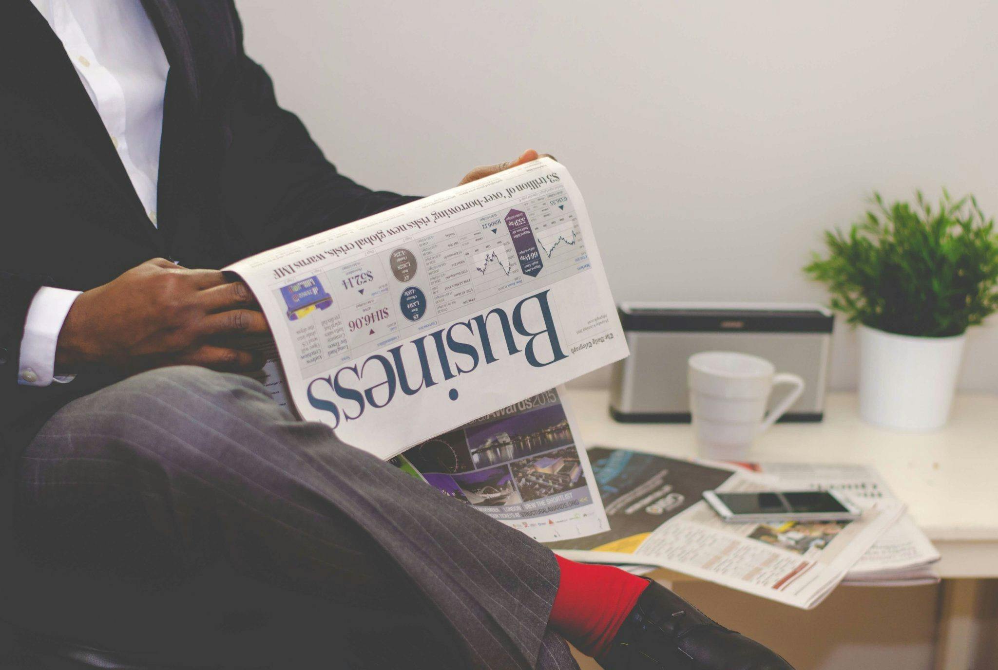 A Black man reads the business section of a newspaper.